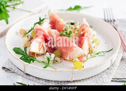 Appetizer with pear, blue cheese and prosciutto ham for holidays on a white plate. Stock Photo