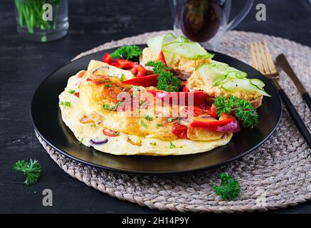 Breakfast. Omelette with paprika, cheese and tomatoes with sandwiches on black plate. Frittata - italian omelet. Stock Photo