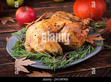 Roasted turkey garnished with cranberries on a rustic style table decorated with pumpkins, apples and autumn leaf. Thanksgiving Day. Stock Photo