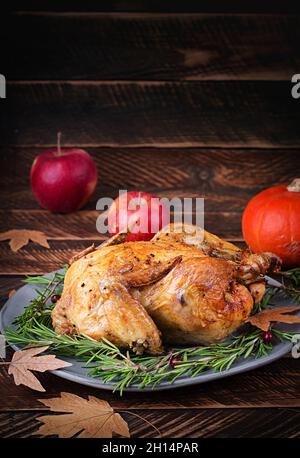 Roasted turkey garnished with cranberries on a rustic style table decorated with pumpkins, apples and autumn leaf. Thanksgiving Day. Stock Photo