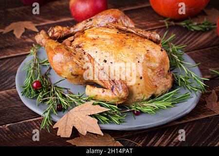 Roasted turkey garnished with cranberries on a rustic style table decorated with pumpkins, apples and autumn leaf. Thanksgiving Day. Stock Photo
