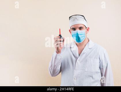 Young doctor in white suit and protective breathing mask with enema in his hand isolated. Stock Photo