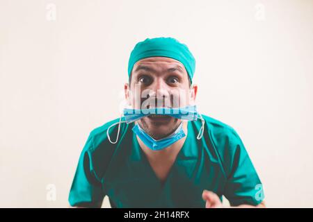 Young doctor in green surgeon suit with protective breathing mask in his mouth isolated Stock Photo