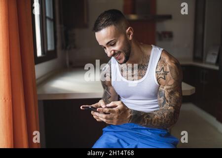 Young fit Caucasian tattooed male using his smartphone Stock Photo