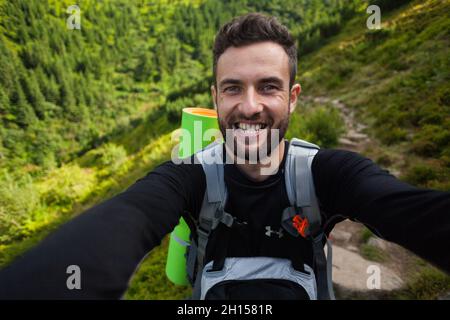 CARPATHIANS, UKRAINE - AUGUST 14, 2016: Young and happy man takes a selfie in Carpathian mountains, Ukraine Stock Photo