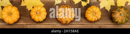 Autumn decor of pumpkin and yellow maple leaves on a wooden background. Halloween decor. Stock Photo