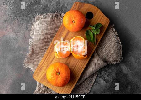 flat lay composition with fresh orange tangerines on a wooden cutting board and dark background, top view Stock Photo