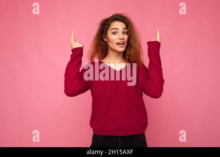 Photo of pretty astonished young woman pointing fingers up at copyspace presenting incredible ads promo with impressed scream wow omg emotions wearing Stock Photo