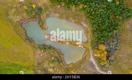 Little lake or pond of unusual shape with a beautiful autumn nature photographed from above with a drone. Real is beautiful Stock Photo