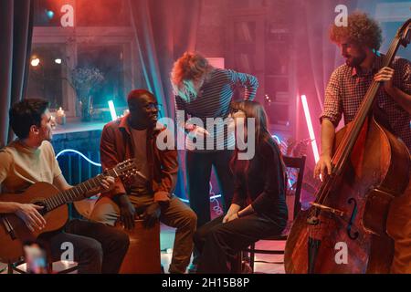 Young people playing instruments and singing while they gathering in music studio Stock Photo