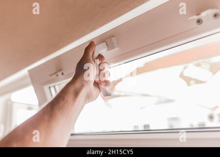 The guy's hand opens a plastic double window for the handle pvc double glazing. Stock Photo