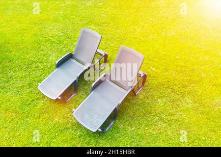 Aerial view sun loungers on a green meadow with short cut lawn grass. Sunbeds on grass at the beach Stock Photo
