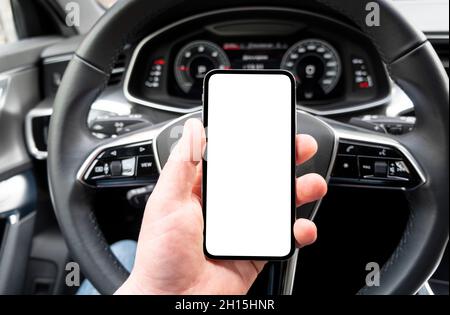 Driver hand using smartphone in car. Smartphone in a car use for Navigate or GPS. Mobile phone with isolated white screen. Blank empty screen. copy sp Stock Photo