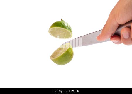 Hand with knife cutting lime in half in the air. clipping path., full depth of field. Stock Photo