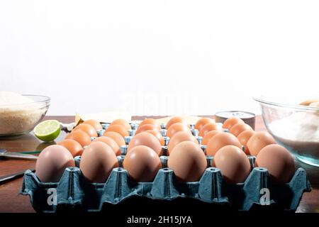 Egg crate or bucket on wooden table. Kitchen ingredients on white and wooden background. Stock Photo