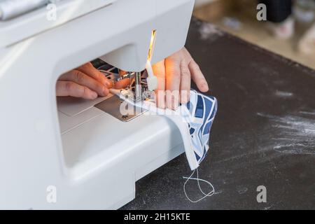 Woman is sewing at home using a sewing machine closeup. Horizontally. Stock Photo