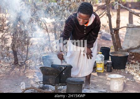 Outdoors kitchen, African woman cooking  pap and Setswa is a traditional African  food from Botswana made from boiled beef and tendons, Stock Photo