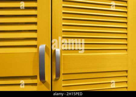 Close-up photo of yellow colored cupboard doors with handles. Stock Photo