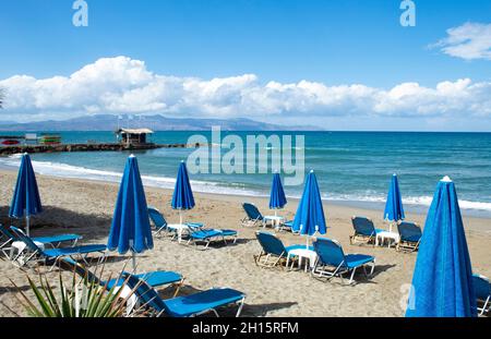 Crete island, Greece Agia Marina beach near Chania Parasols and sun loungers on the sands Stock Photo