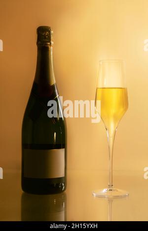 A champagne bottle with empy label with a champagne glass on a yellow background Stock Photo