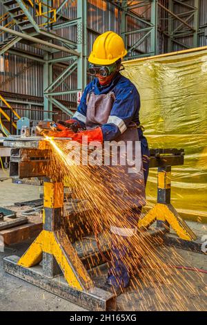 Woman African worker with red gloves  cutting with a torch corner metal in a steel factory in Botswana Africa Stock Photo