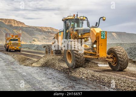 A grader and a truck repairing the road and putting water on a road in a diamond mine in Jwaneng, Botswana Stock Photo