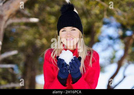 Blonde woman blowing a snowball in winter, in Sierra Nevada, Granada, Spain. Stock Photo