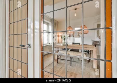 Through fenced window view of contemporary dining room with table under lamps at home Stock Photo
