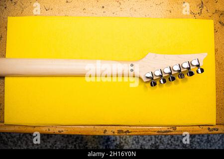 From above of new wooden guitar neck placed on yellow surface on table Stock Photo