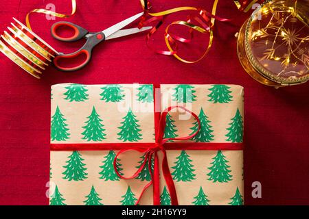 Family preparing for Christmas. Top view of hands wrapping gifts. Boxes with presents, colorful wrapping paper, scissors and ribbons. Stock Photo