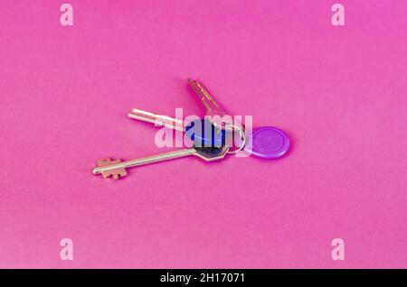 A bunch of door keys on a colored background. Three keys to the new dwelling and a code keychain for the intercom.  Selective focus. Stock Photo