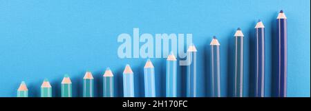 Pencils of different shades lie on blue background Stock Photo