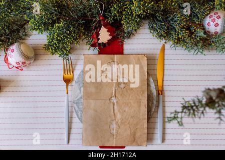 From above red holiday place setting with empty menu on white tablecloth Stock Photo