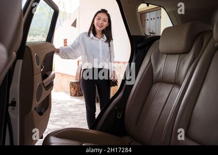 https://l450v.alamy.com/450v/2h17284/front-view-of-smile-asian-female-passenger-talking-to-a-cab-driver-from-the-back-of-the-car-and-with-the-door-open-2h17284.jpg