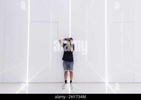 High angle side view of slim female bending back in Ustrasana and shooting live video on smartphone during yoga training Stock Photo