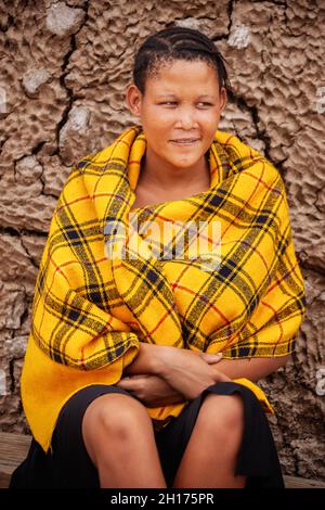 an young bushman girl from Central Kalahari, village New Xade in Botswana, in front of  a blanket her shack Stock Photo