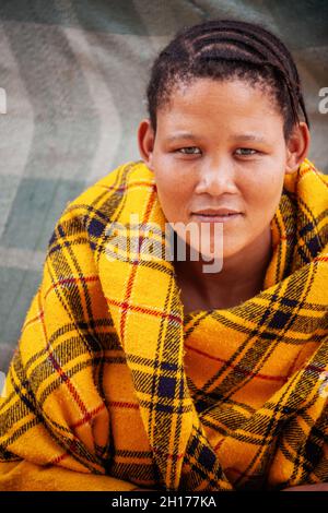 an young bushman girl from Central Kalahari, village New Xade in Botswana, in front of  a blanket her shack Stock Photo