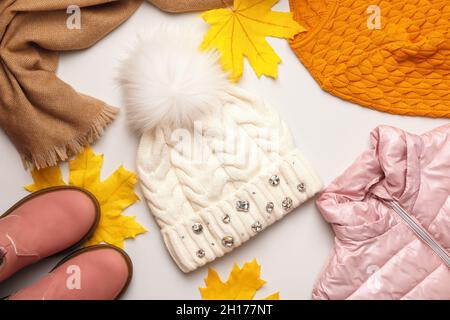 A set of warm autumn-winter clothes with fallen maple leaves on a white background. Hat jacket scarf boots sweater. Flat lay top view Stock Photo