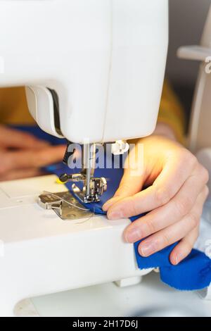 Female seamstress sewing or stitching fabric with professional machine Stock Photo