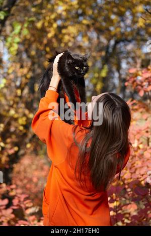 Young woman with black cat in autumn park Stock Photo