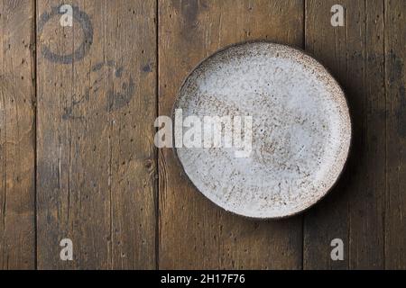 Clean empty ceramic plate on dark brown wooden background. Horizontal, above, copy space Stock Photo
