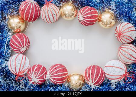 Red white and gold Christmas balls and blue tinsel are stacked in the form of frame on a white background. Christmas mockup Stock Photo