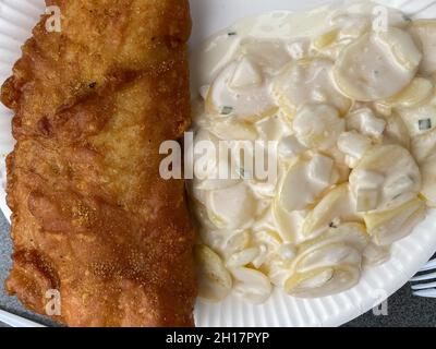 Closeup of isolated breaded fried fish with greasy mayonnaise potato salad on white paper plate in dutch fast food restaurant Stock Photo