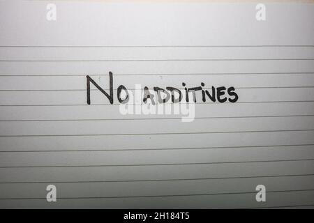 A closeup shot of a handwritten note saying 'No additives' on a white notepaper Stock Photo