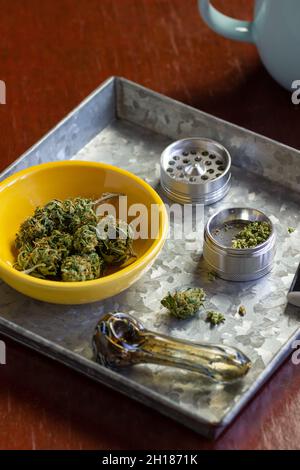 Medical Marijuana Buds or Hemp Flowers with Herb Grinder and Smoking Accessories in Metal Tray with Coffee Mug Stock Photo