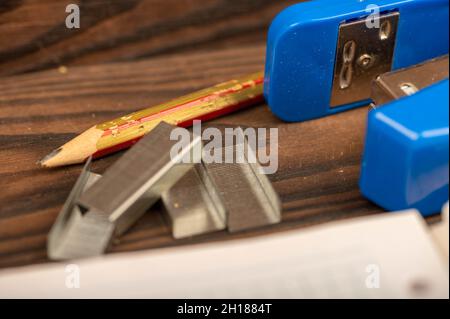 Office stapler, stapler staples and white paper on the table, close-up, selective focus Stock Photo