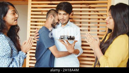 A shot of four South Asian friends in India celebrating a birthday with a chocolate cake Stock Photo