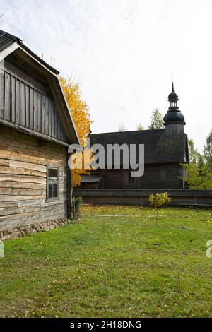 An old rustic wooden hut. In the background there is a rustic wooden church. Stock Photo