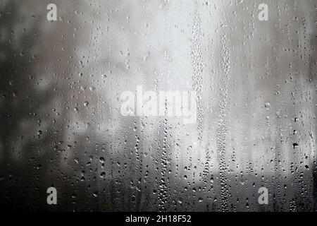 Landscape with many raindrops through house window and blurred trees on gloomy rainy autumn day Stock Photo