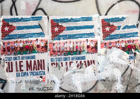 Gli Stati Uniti Affamano Giu le Mani da Cuba Socialista. Torn political wheatpaste posters on wall in Rome, Italy.